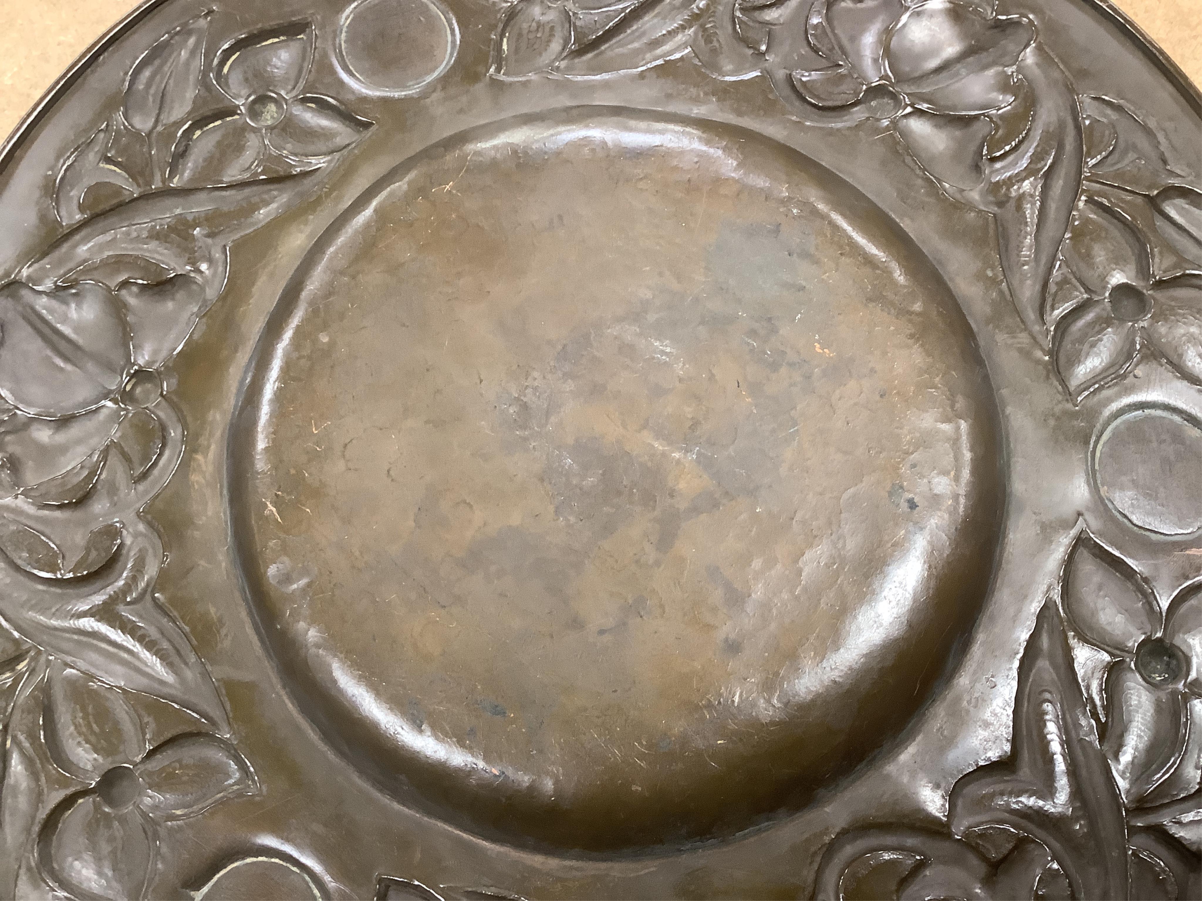 An Arts and Crafts embossed copper dish, in the manner of John Pearson, inlaid with Ruskin cabochons, unsigned, 32cm in diameter